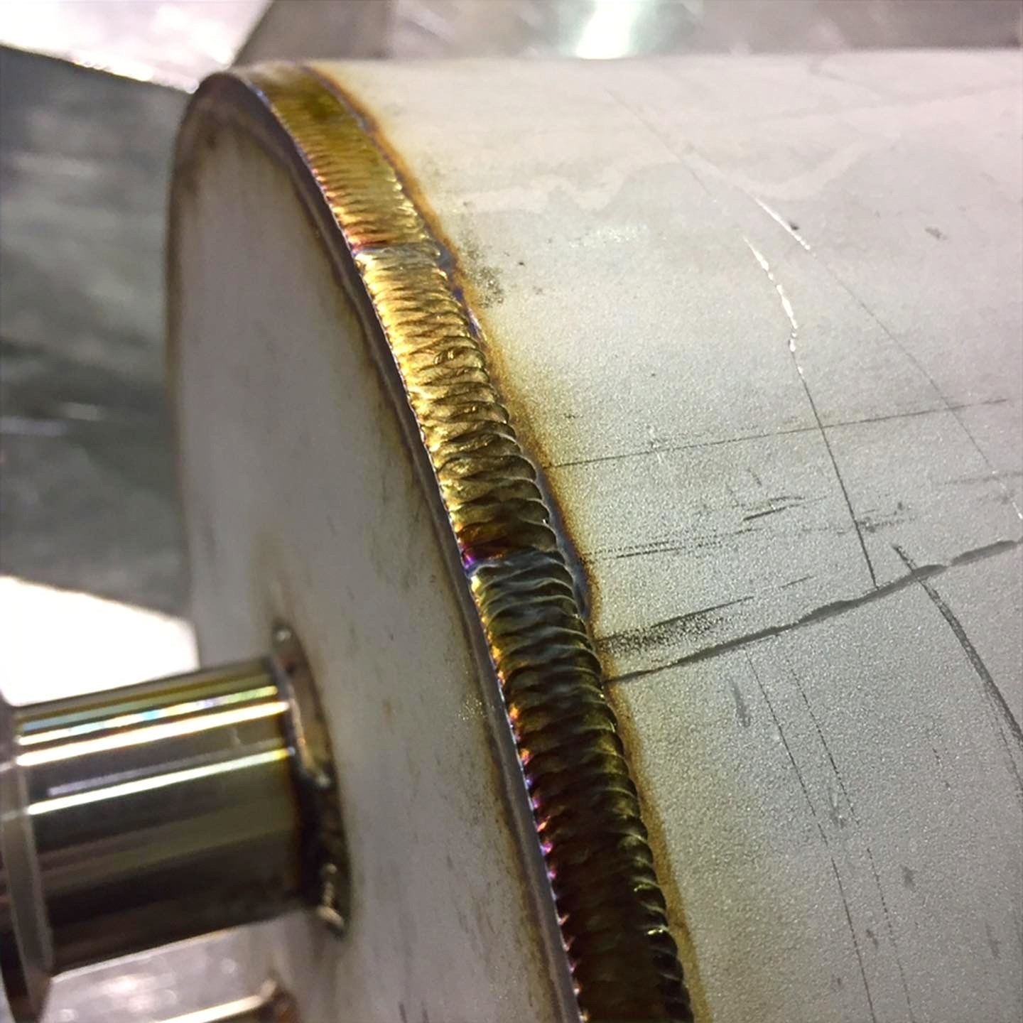 Extreme close-up of a stainless steel TIG weld with gold oxidation