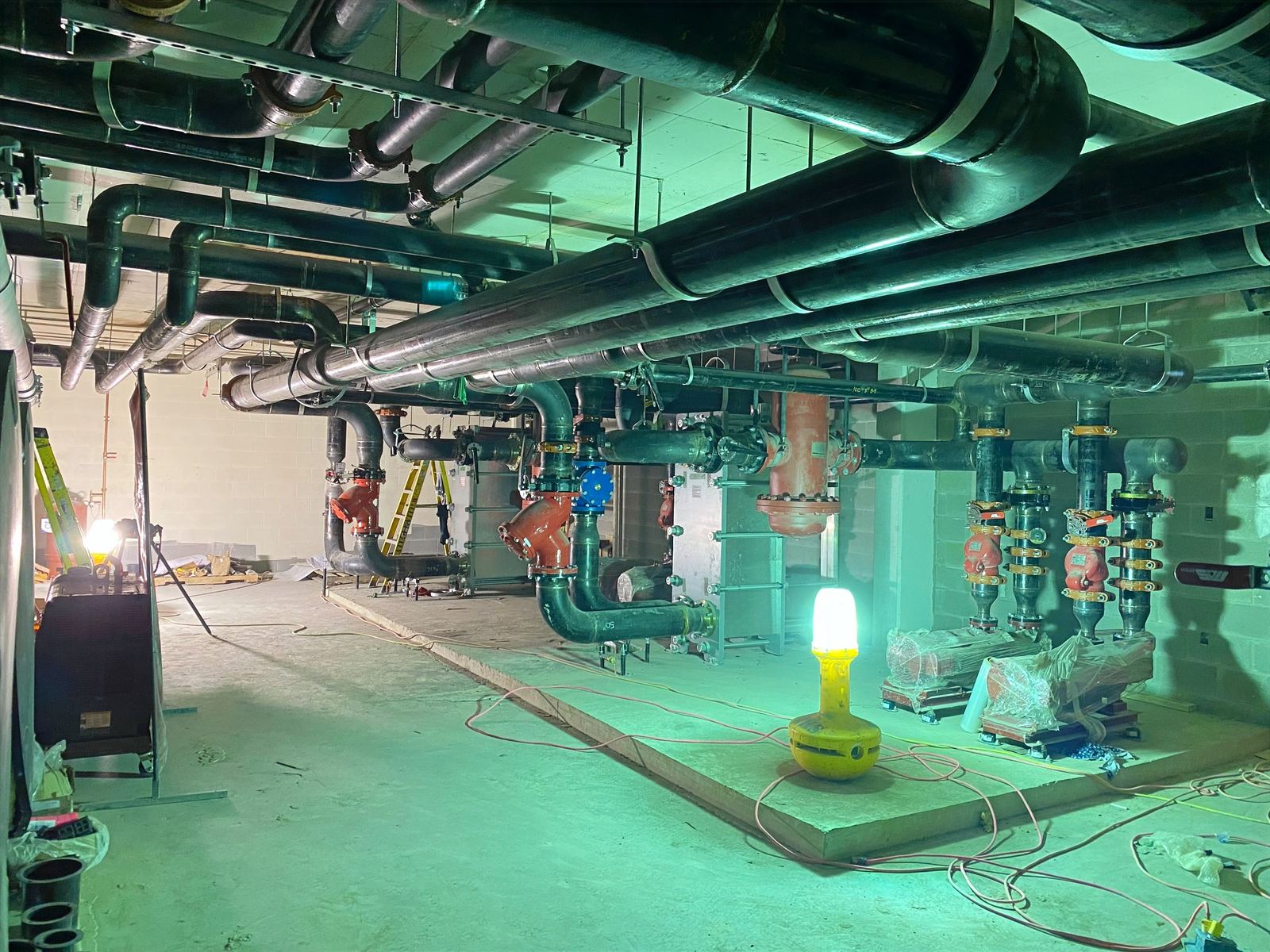 Newly installed pipe system in a green-lit commercial mechanical room