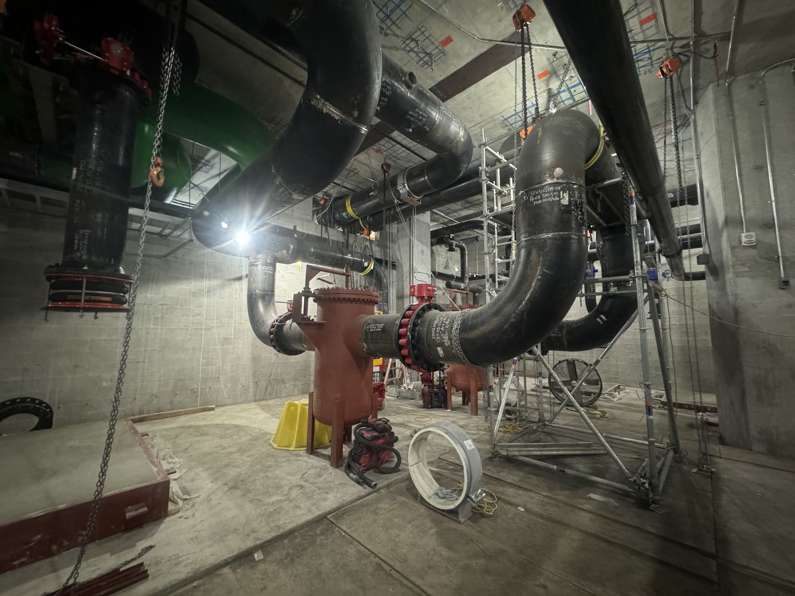 Large-diameter black carbon steel pipe elbow with a red valve on a commercial install