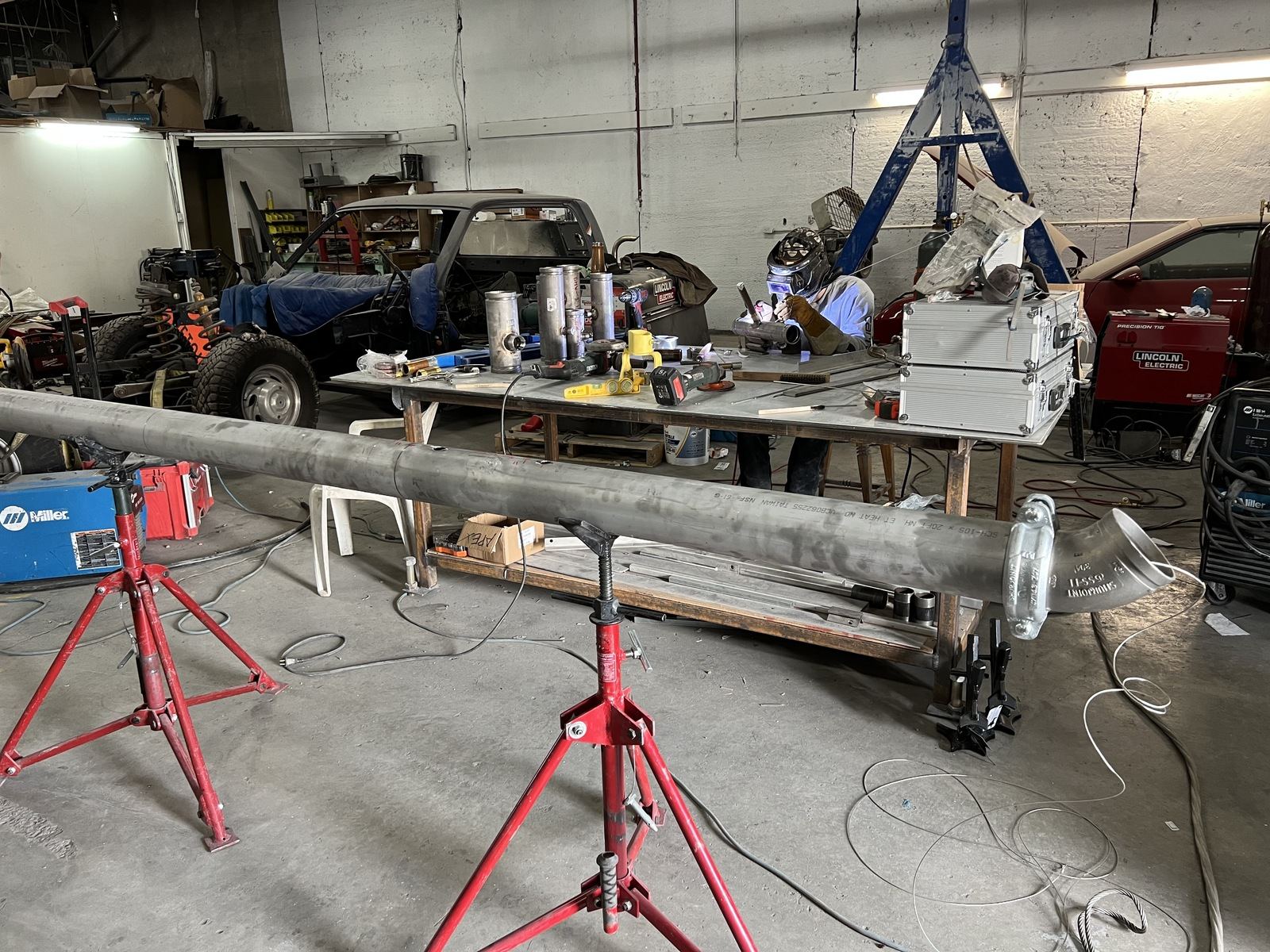 Welding and fabrication shop with a long tube assembly on red pipe stands