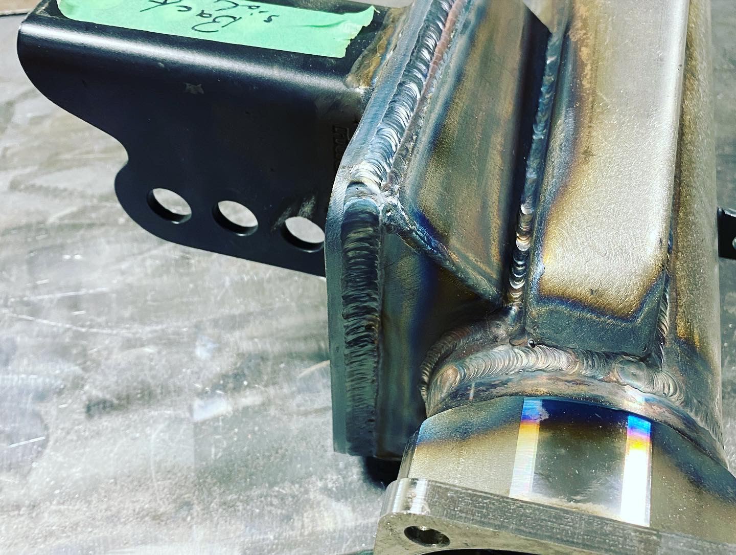 Close-up of a stainless steel TIG weld with blue and gold heat tint on a fabricated part