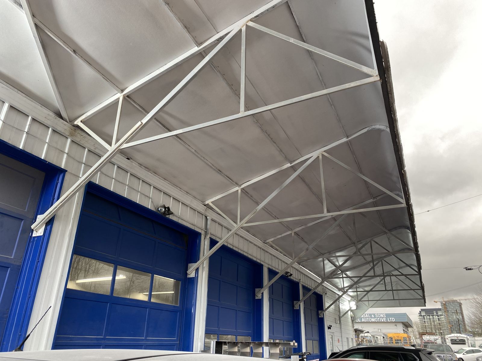 Steel truss canopy over the blue loading doors of a commercial building
