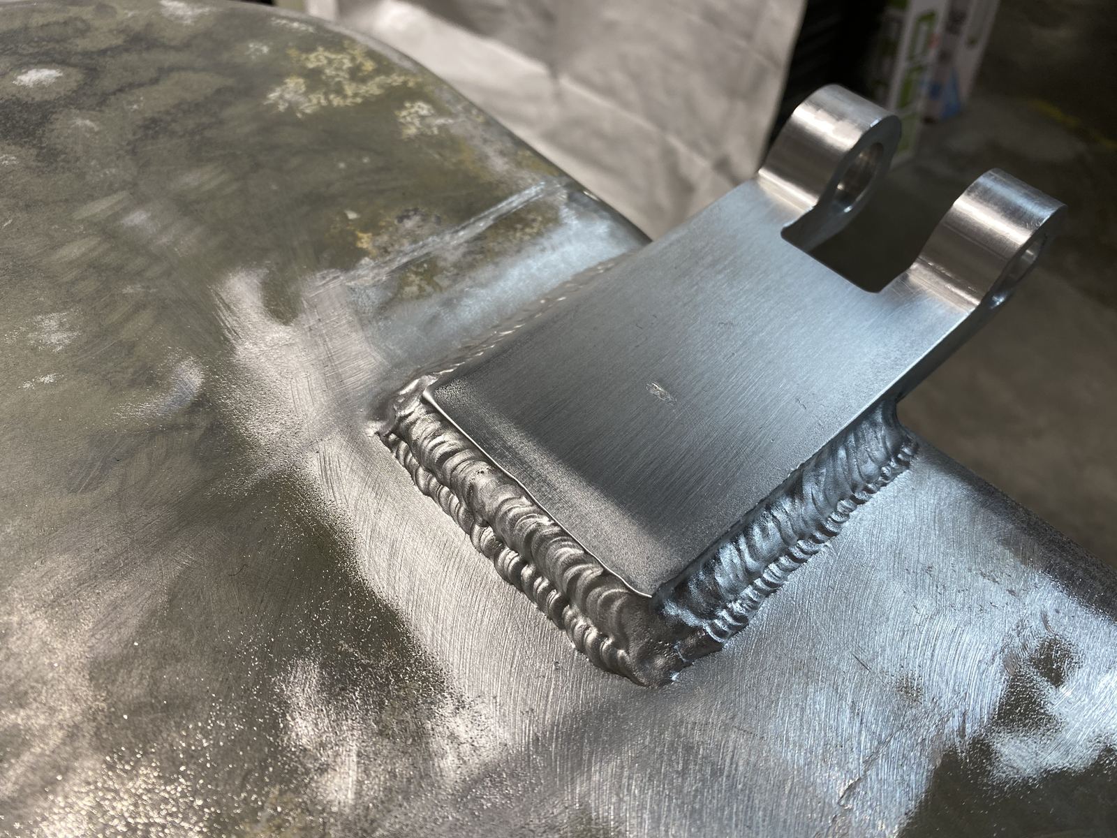 Close-up of a TIG-welded aluminum hinge plate with a clean, even bead